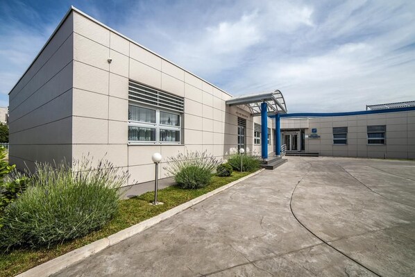 A modern building with a flat facade, large windows, and a covered entrance area.