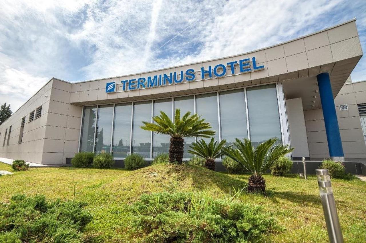 A modern hotel building with a large glass facade and a sign reading 'Terminus Hotel'.