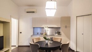 Een moderne keuken met witte kastjes, een centraal eiland en een eethoek met een ronde tafel en stoelen.
