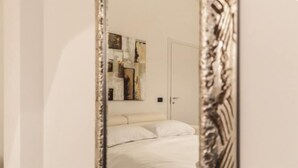 Een slaapkamer met een bed, een deur en een abstract kunstwerk aan de muur.