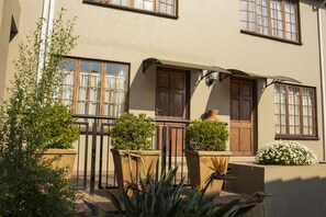 A building with multiple windows, a wooden door, and potted plants.