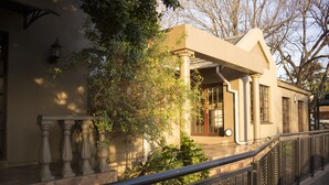 A building with a beige facade, a balcony with balustrades, and a tree in the foreground. - Ruth Avenue Guest House (Edenvale)
