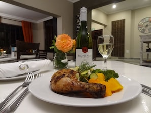 A dining table with a plate of food, a bottle of wine, and a glass of white wine.