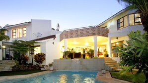 A modern house with a swimming pool, a covered patio, and a well-maintained garden.