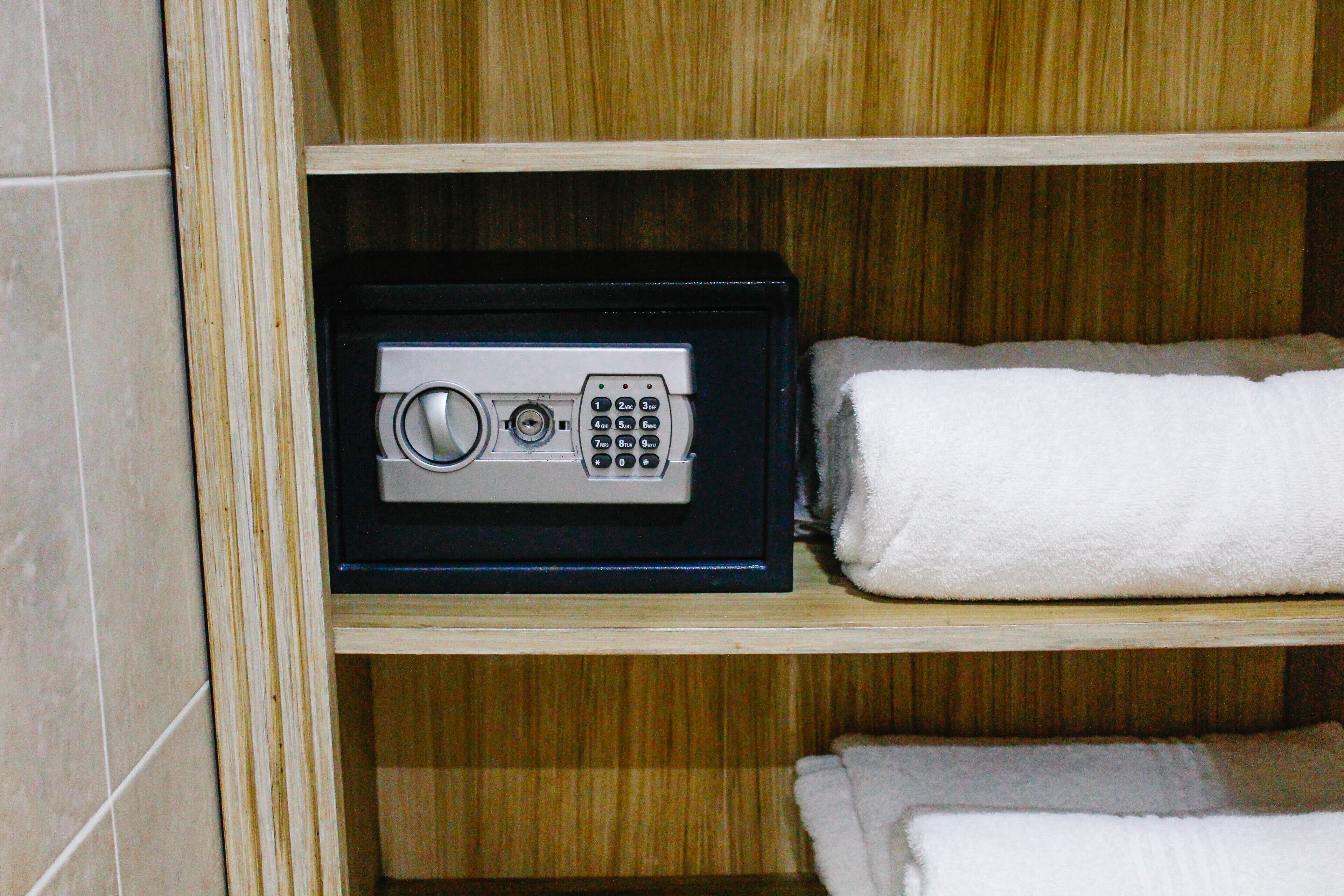 A wooden shelf with a safe and towels.