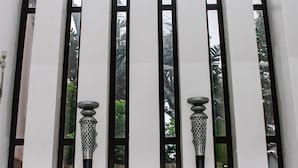 A white wall with five vertical black frames, each containing a decorative metal object.