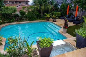 A swimming pool surrounded by lush greenery and a wooden fence.