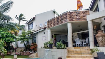 Una casa moderna con piscina, un porche cubierto y una escalera que lleva a la entrada.