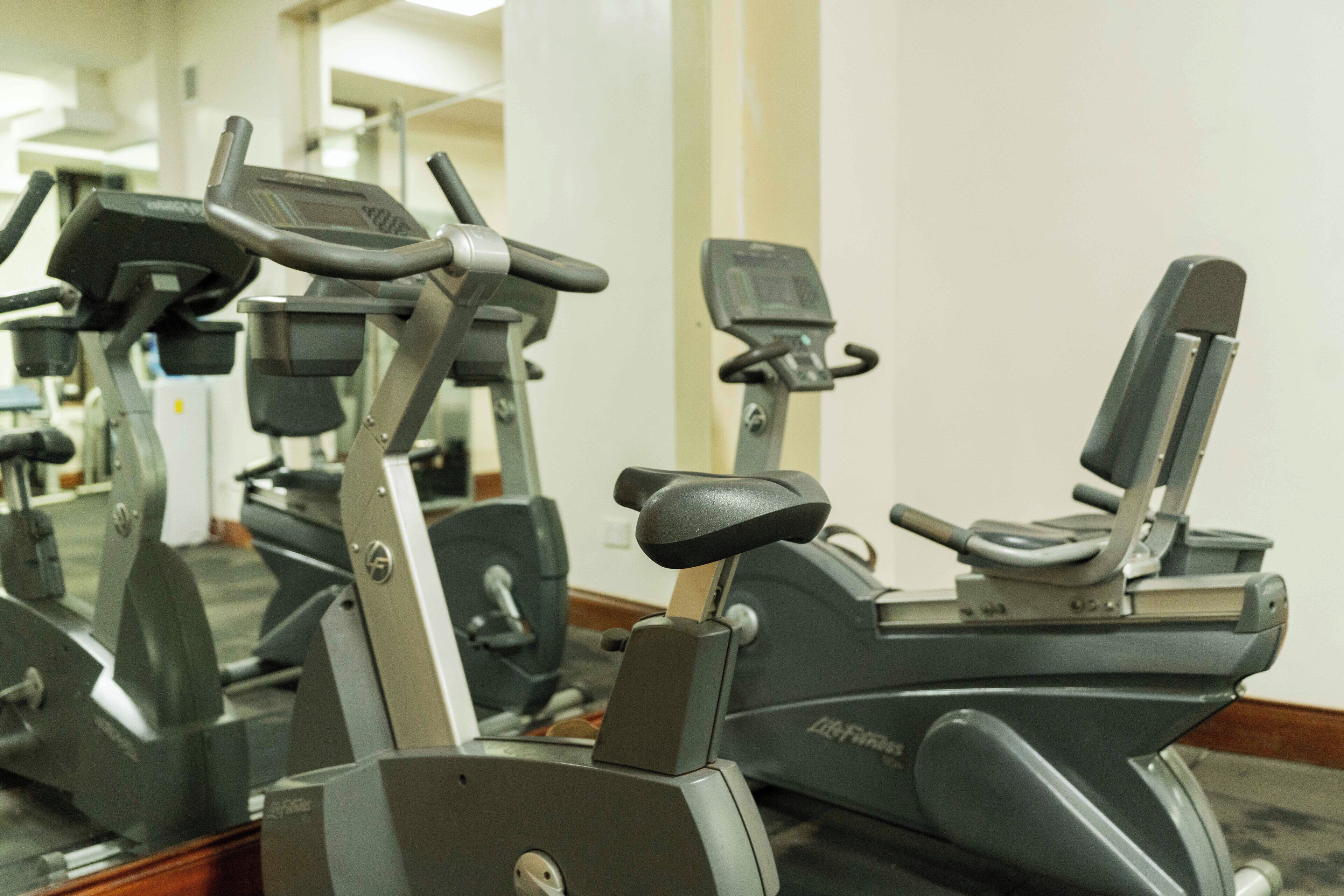 Une rangée de vélos d’appartement dans une salle de sport, les murs étant recouverts de miroirs.