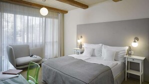 Een hotelkamer met een bed, een stoel, een bureau en een lamp.