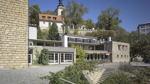Ein Steinhaus mit einem modernen Anbau, einem Glockenturm und einer Treppe, die nach oben führt.