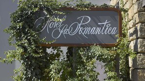 Een bord met de tekst 'Hotel La Romantica', overgroeid met klimop.