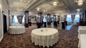 A spacious banquet hall with round tables covered in white tablecloths, elegant chandeliers, and a patterned carpet. - Hotel Select (Sibiu)