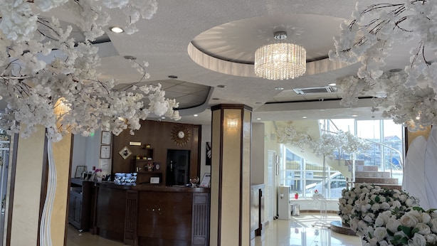 A hotel lobby with a reception desk, a chandelier, and white floral decorations. - Hotel Select (Sibiu)