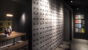 A modern interior with a patterned wall, a wooden table with bottles, and a bench. - Attitude On Granville (Kowloon)