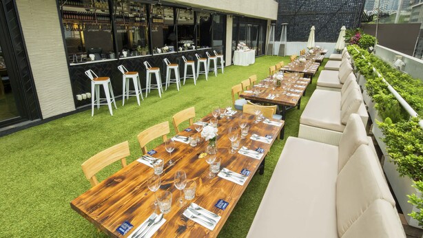 An outdoor dining area with multiple tables and chairs, a bar, and a green lawn. - Attitude On Granville (Kowloon)