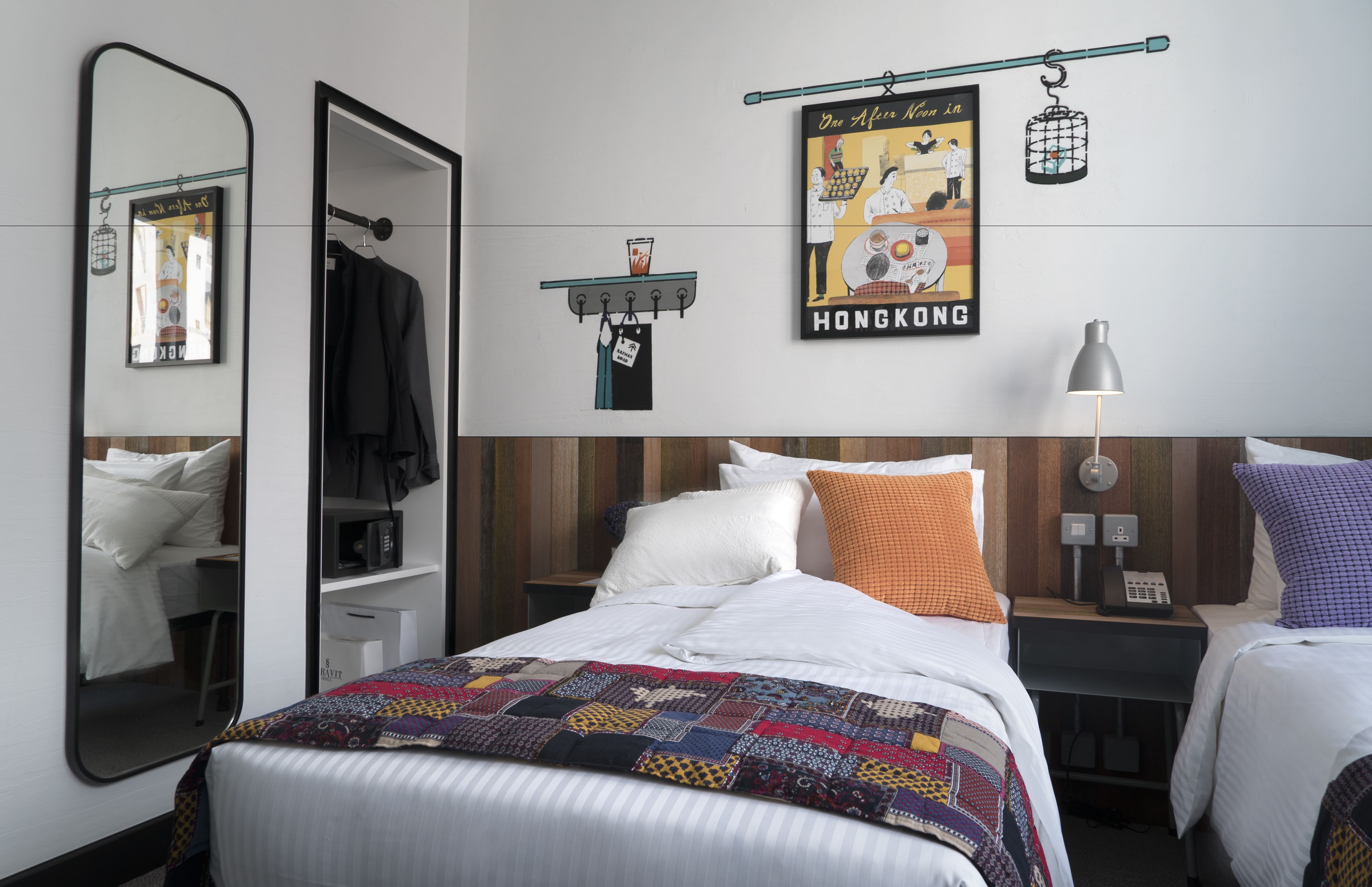 Habitación de hotel con cama, mesita de noche, espejo, lámpara colgante y un cartel en la pared.
