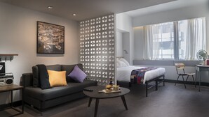 A modern hotel room with a sofa, a bed, a desk, and a window with curtains. - Attitude On Granville (Kowloon)