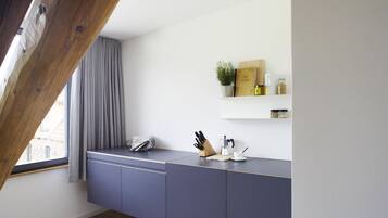 Eine moderne Küche mit grauer Arbeitsplatte, Holzboden und einem Fenster mit grauen Vorhängen.