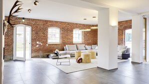 A spacious living area with a brick wall, a sofa set, and a large window. - WohnGut Wolfsburg (Wolfsburg)