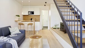 A modern living room with a grey sofa, a coffee table, and a staircase with a wooden railing. - WohnGut Wolfsburg (Wolfsburg)