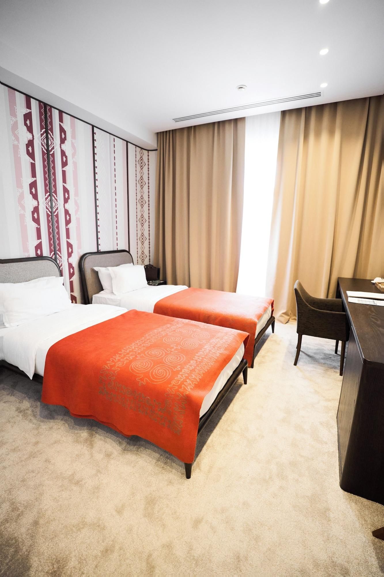 A hotel room with two beds, a desk, and a chair.