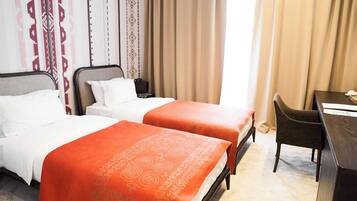 A hotel room with two beds, a desk, and a chair.