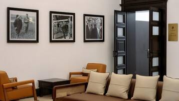 Una habitación con sofá, sillas y una mesa. Hay tres fotografías enmarcadas en la pared.