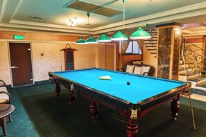 Une table de billard avec des billes, une chaise et un escalier muni d’une rampe.