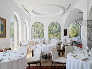A restaurant with round tables, white tablecloths, and chairs. - Kainar Hotel (Shymkent)