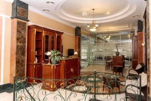 A lobby with a reception desk, seating area, and a glass partition. - Kainar Hotel (Shymkent)