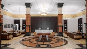 A lobby with a reception desk, seating area, and a chandelier.