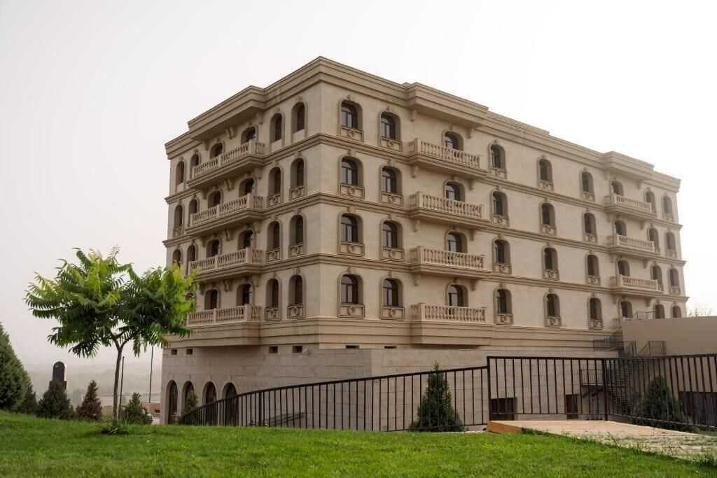 A multi-story building with balconies, a flat roof, and a gated entrance.