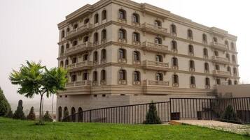 A multi-story building with balconies, a flat roof, and a gated entrance.