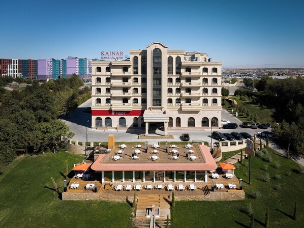 A multi-story hotel with a central courtyard, outdoor seating area, and a parking lot.
