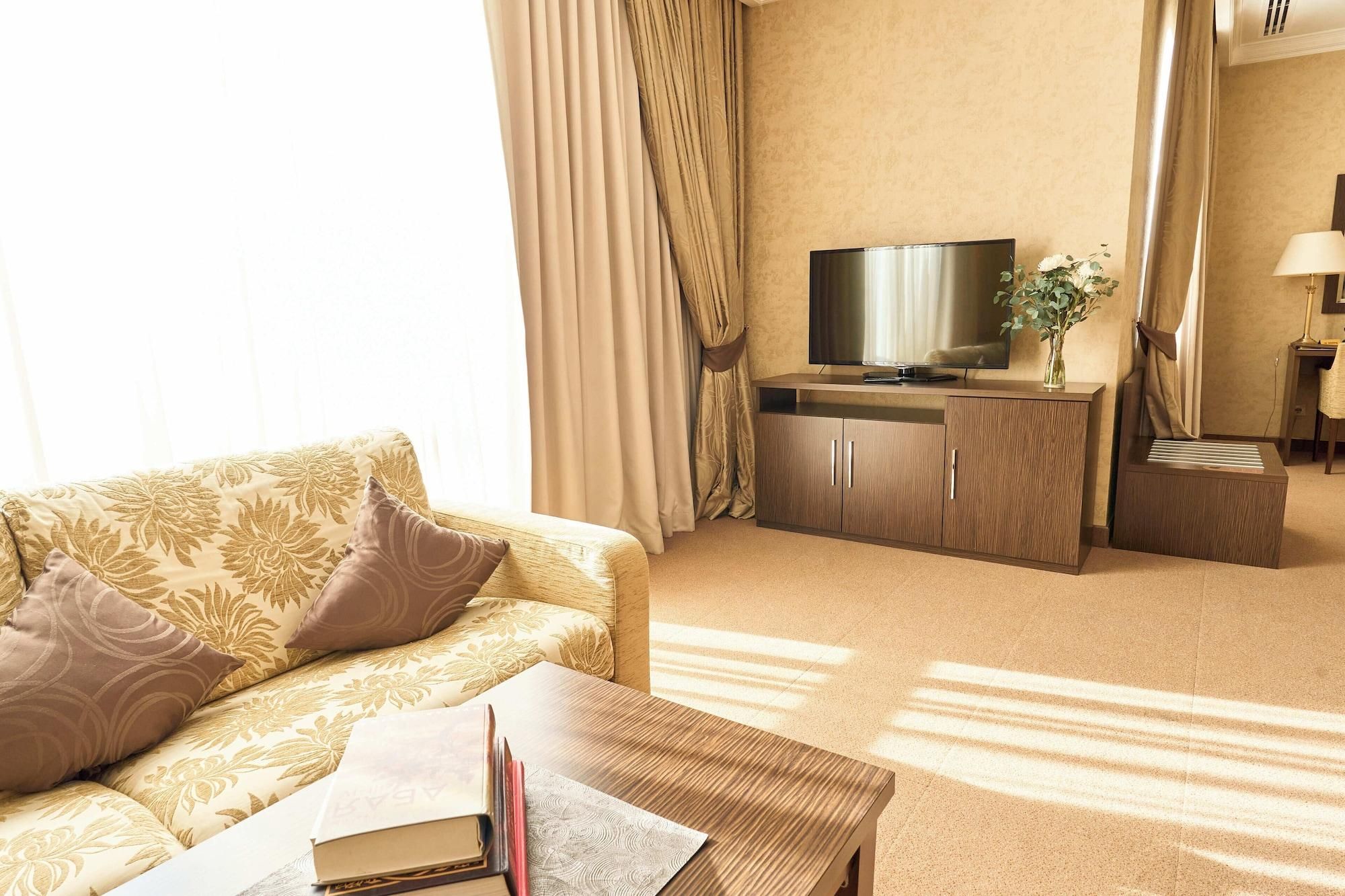 Habitació d'hotel amb sofà, televisió, escriptori i làmpada.
