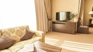 Habitació d'hotel amb sofà, televisió, escriptori i làmpada.