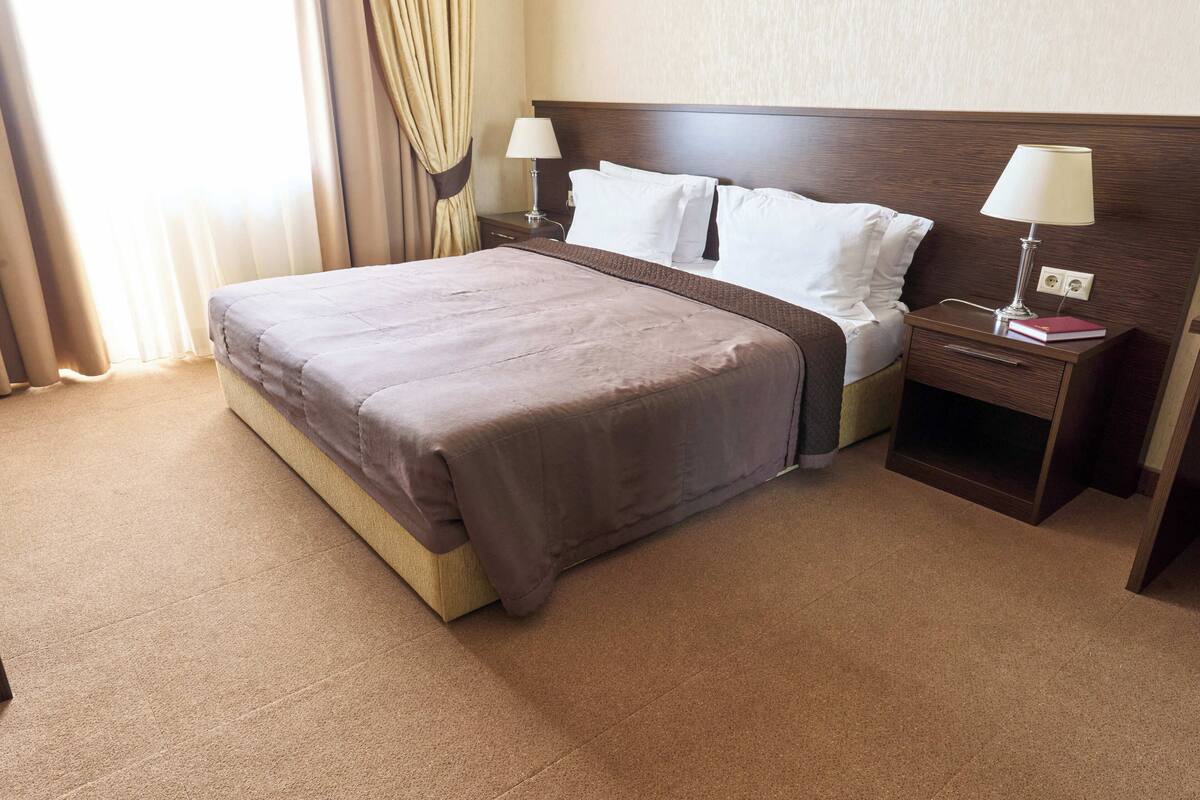 A hotel room with a large bed, two bedside tables, and a nightstand.