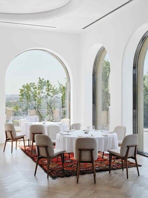 A dining area with a round table, six chairs, and a red patterned rug. - Kainar Hotel (Shymkent)
