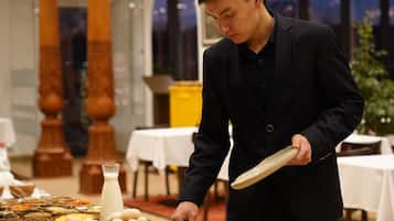 A buffet setup with various food items and a person serving.