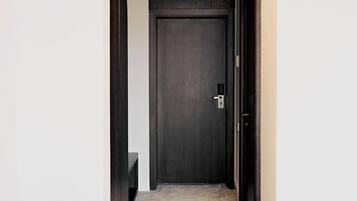 A narrow hallway with a dark wooden door at the end, a small table, and a chair.