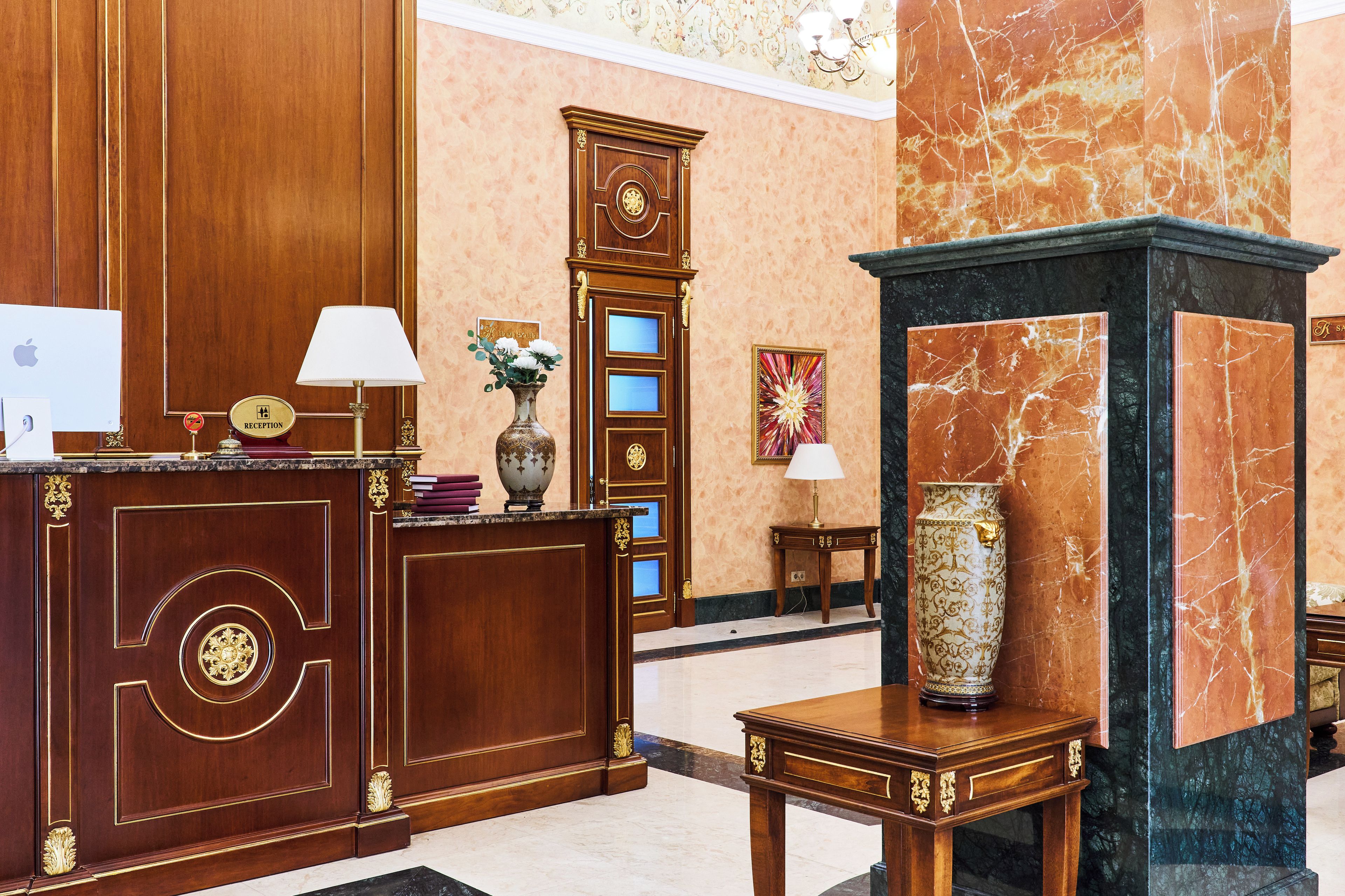 A reception area with a wooden desk, a clock, and a vase with flowers.