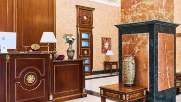 A reception area with a wooden desk, a clock, and a vase with flowers.