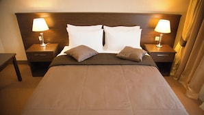 Quarto de hotel com uma cama grande, duas mesas de cabeceira e luminárias.
