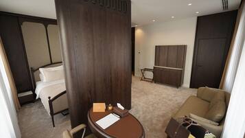 A hotel room with a bed, a desk, a chair, a sofa, and a wardrobe.