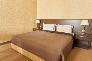 A hotel room with a large bed, two bedside tables with lamps, and a wooden headboard.