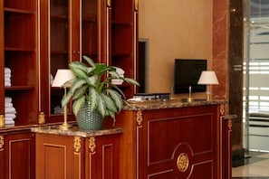 A reception desk with a potted plant, two lamps, and a television.