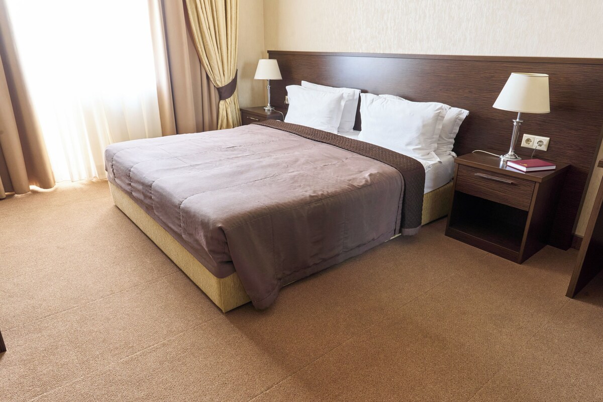 A hotel room with a large bed, two bedside tables, and a nightstand.