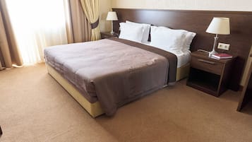 A hotel room with a large bed, two bedside tables, and a nightstand.