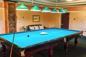 A pool table with a green felt surface, surrounded by a wooden frame with red accents.